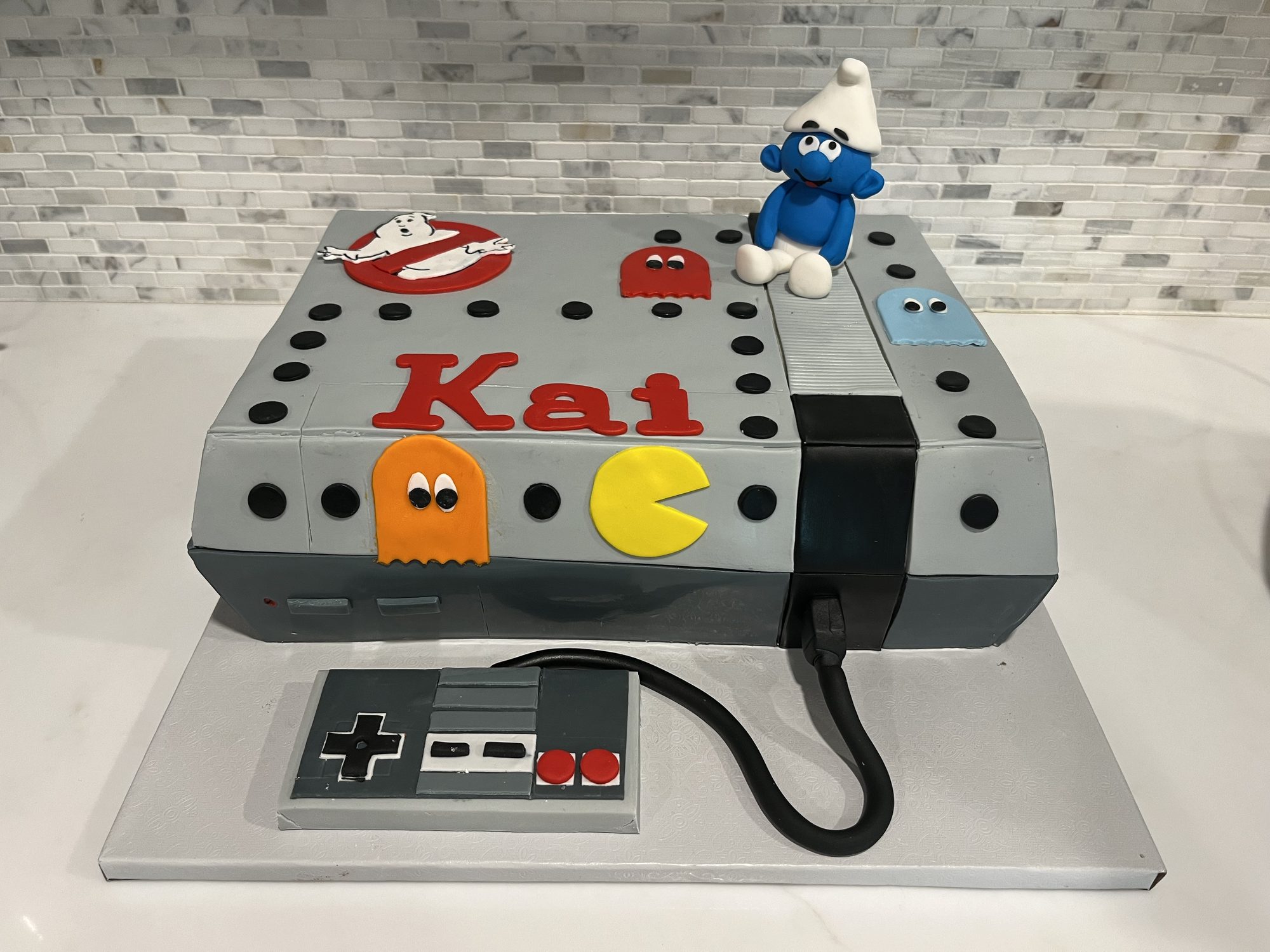 Sculpted Nintendo console cake with Pac-Man and a Smurf